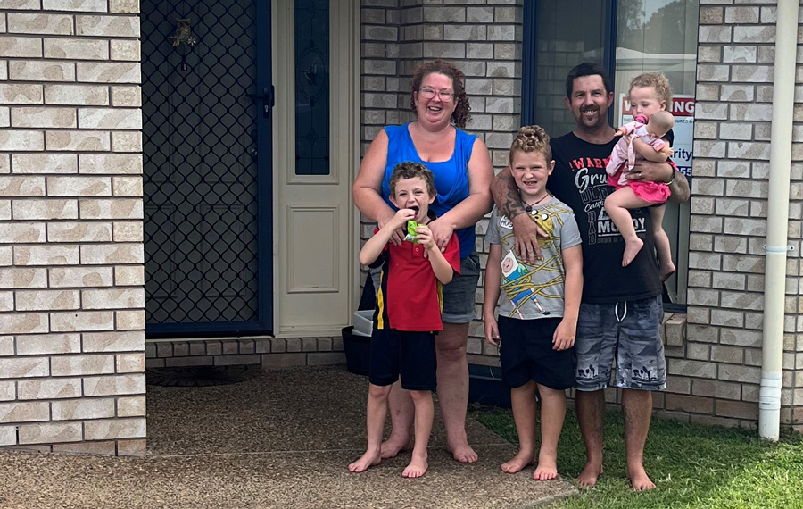 Amy and Floyd standing at the front door of their Bundaberg suburban 4-bedroom home 