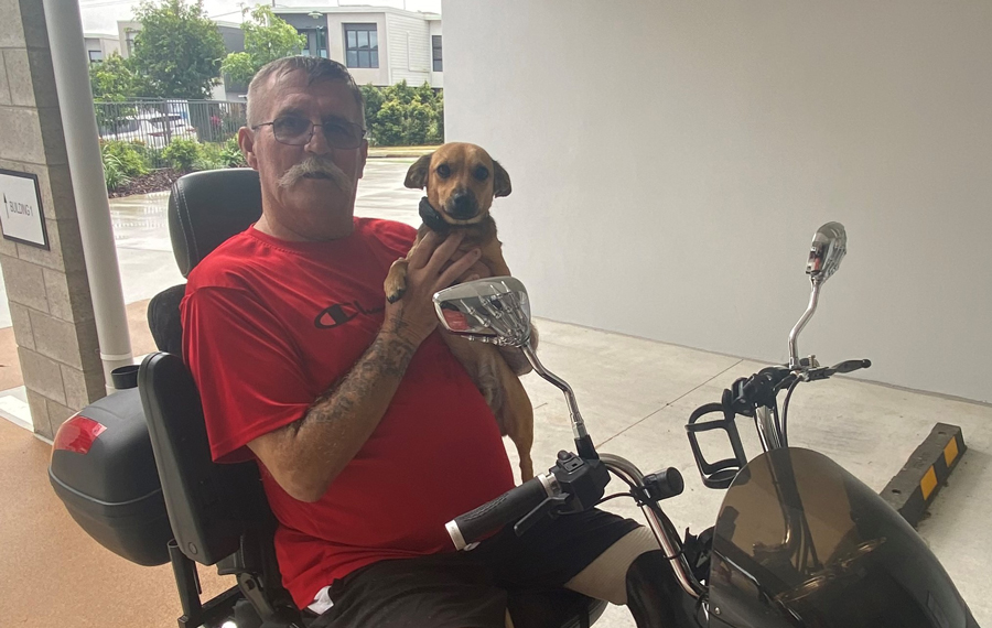 Man with dog on mobility scooter in an accessible social housing complex.